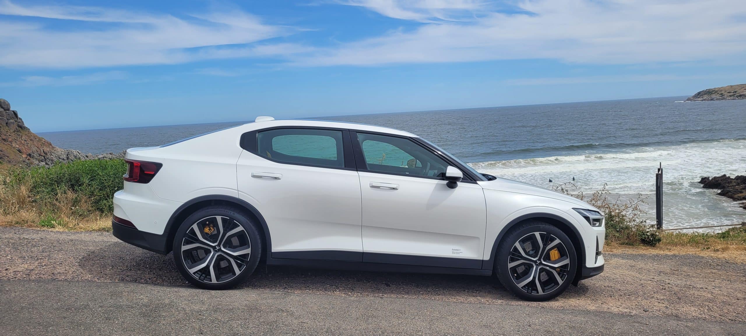 Snow coloured Polestar 2 dual motor EV with performance pack side view by the sea