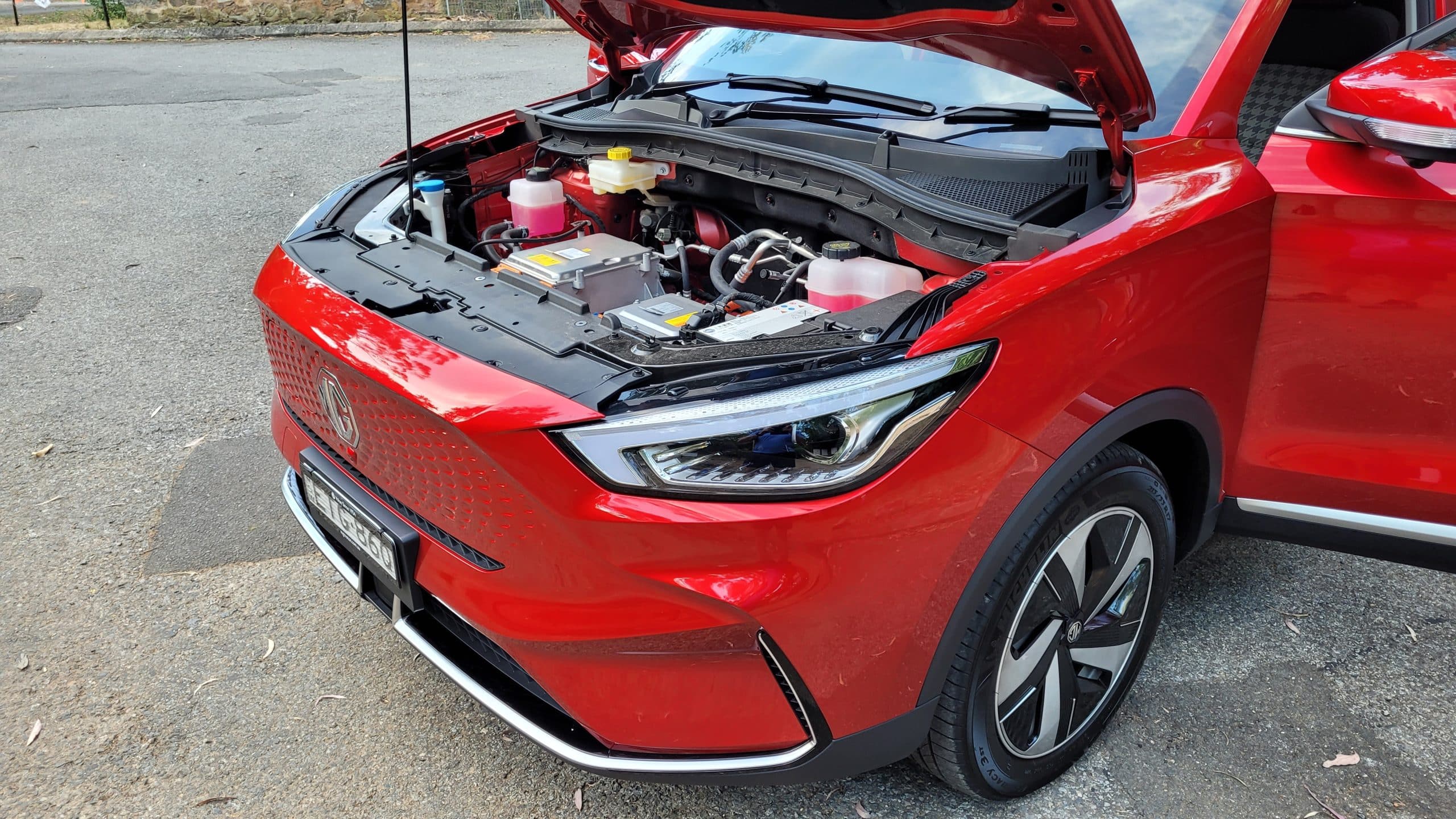 Front angle view of red MG ZS EV with open bonnet