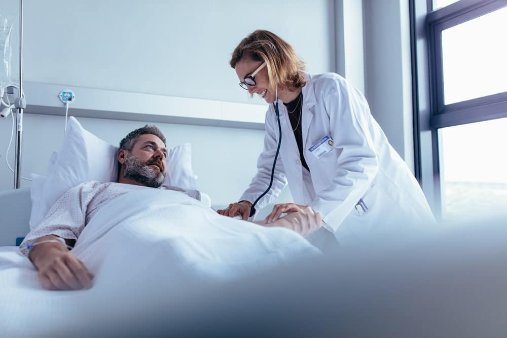 A man lying in a hospital bed being treated by a doctor