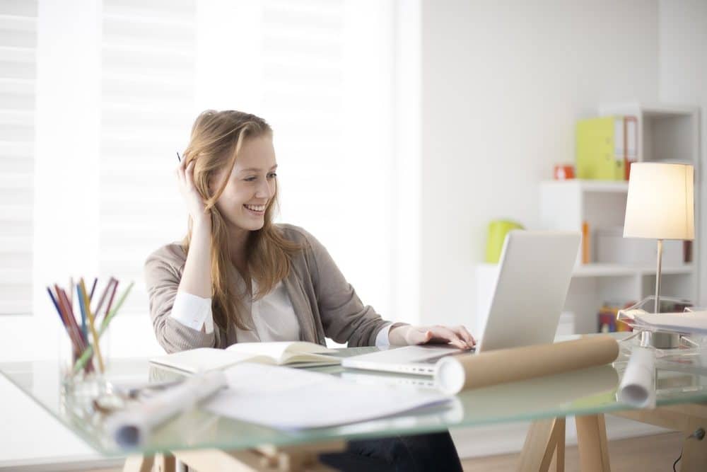 Health Insurance Banner - Young woman sitting at her desk looking at customised health insurance on her laptop