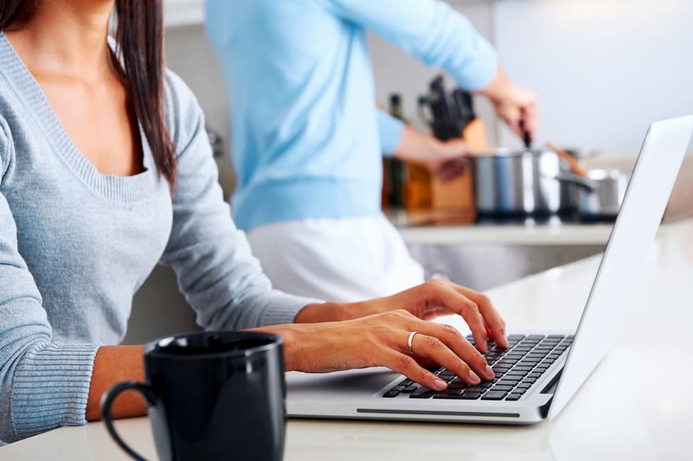 Life Insurance Banner - Close up of a woman on her laptop next to the kitchen