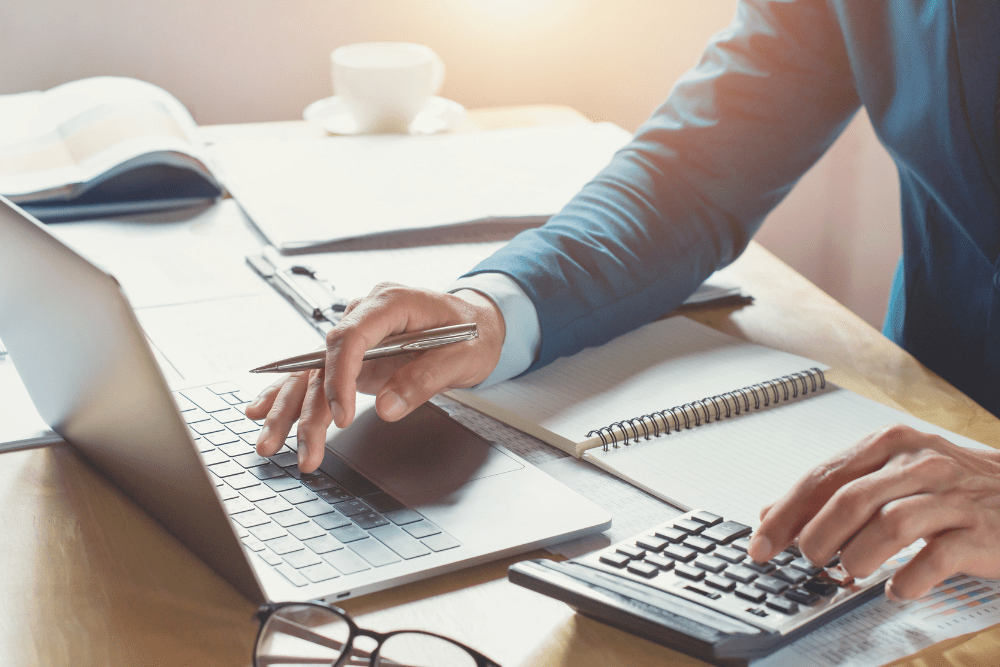 Businessperson using a calculator and laptop