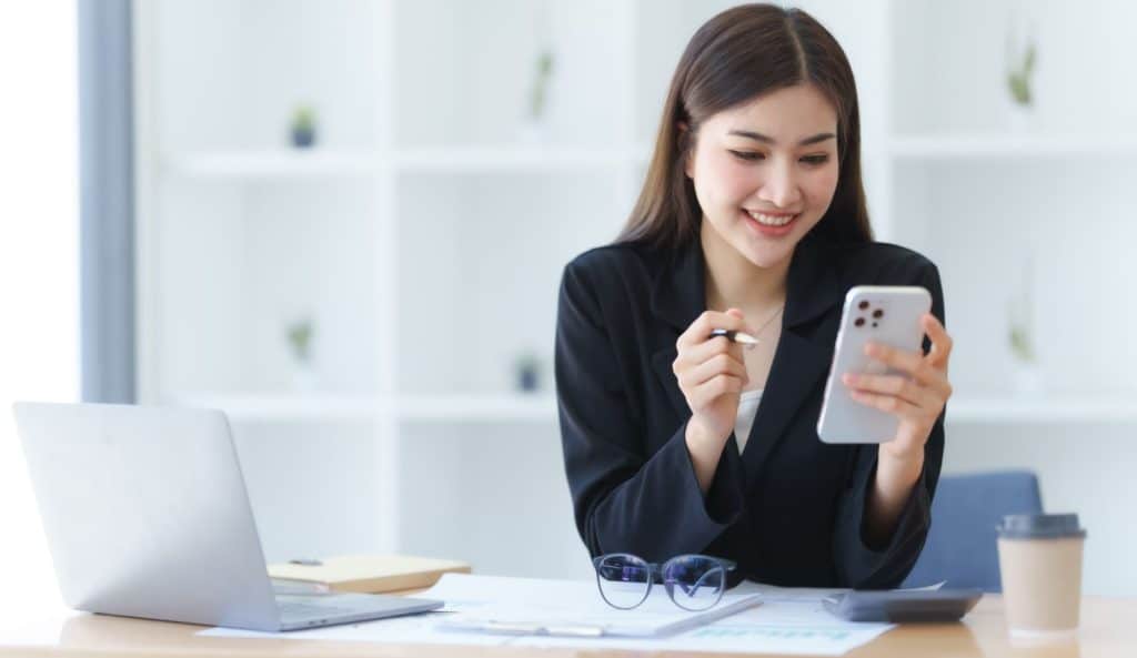 Woman of asian descent, smiling while using phone