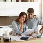 Concerned couple look over their mortgage payment printout in their kitchen