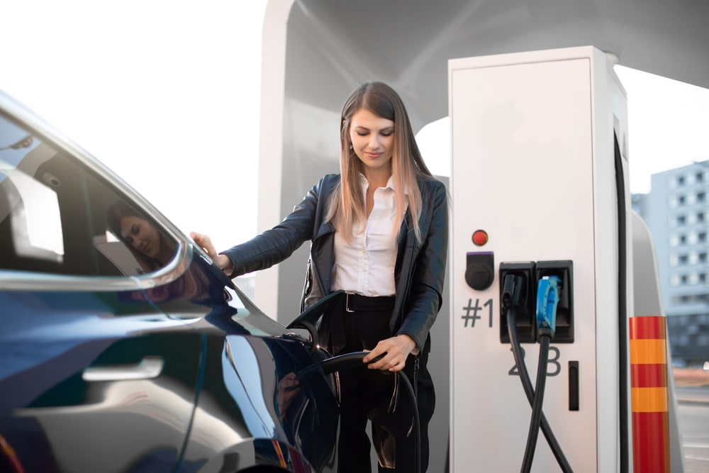 Woman charging her electric car at a petrol station