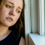 Close up of a stressed and unhappy young Australian woman looking out the window