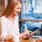 Small Loans Banner - Smiling young woman looking at her tablet in a cafe