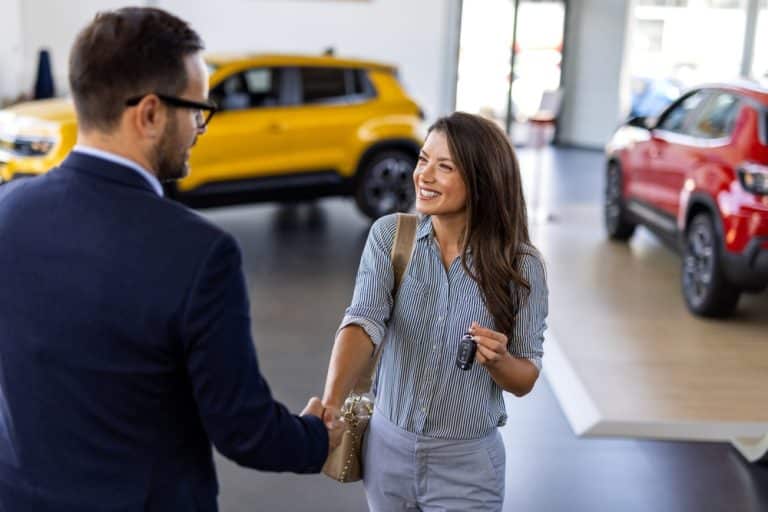 Woman shaking hands with dealer after buying new car
