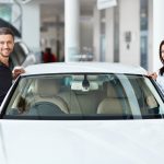 Man and woman getting into new car