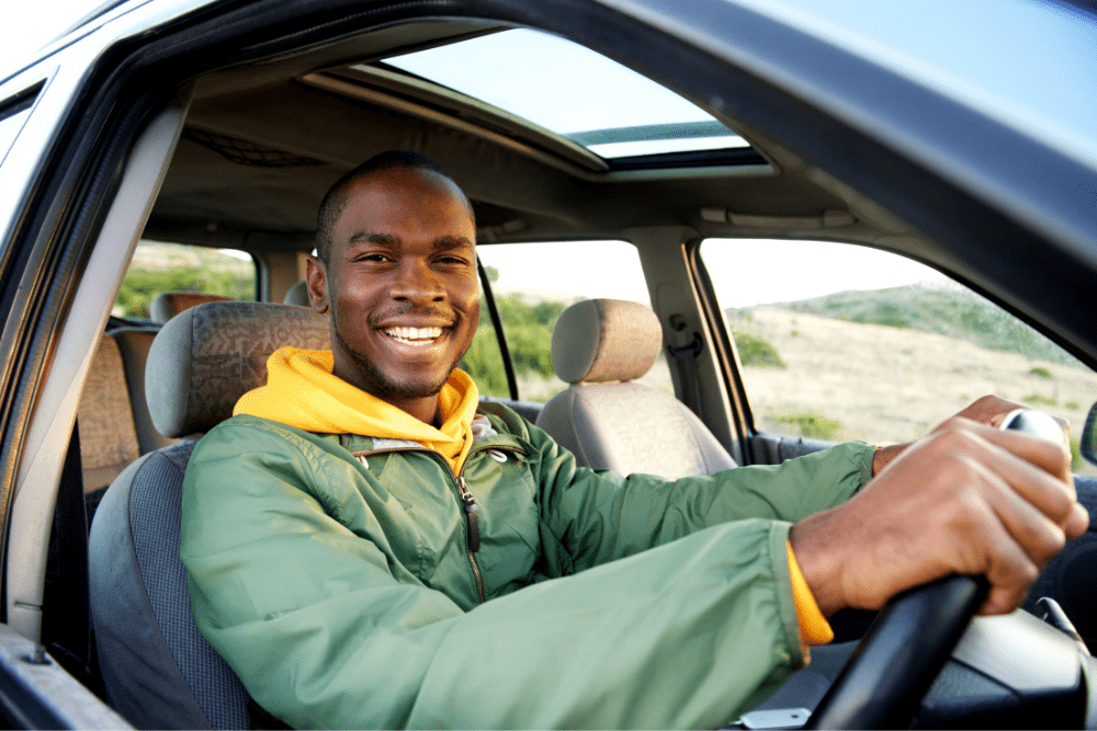 Car Loans Banner - Man smiling while driving a car