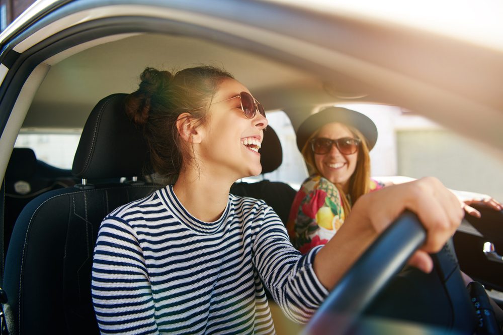 Happy women driving in sunny car