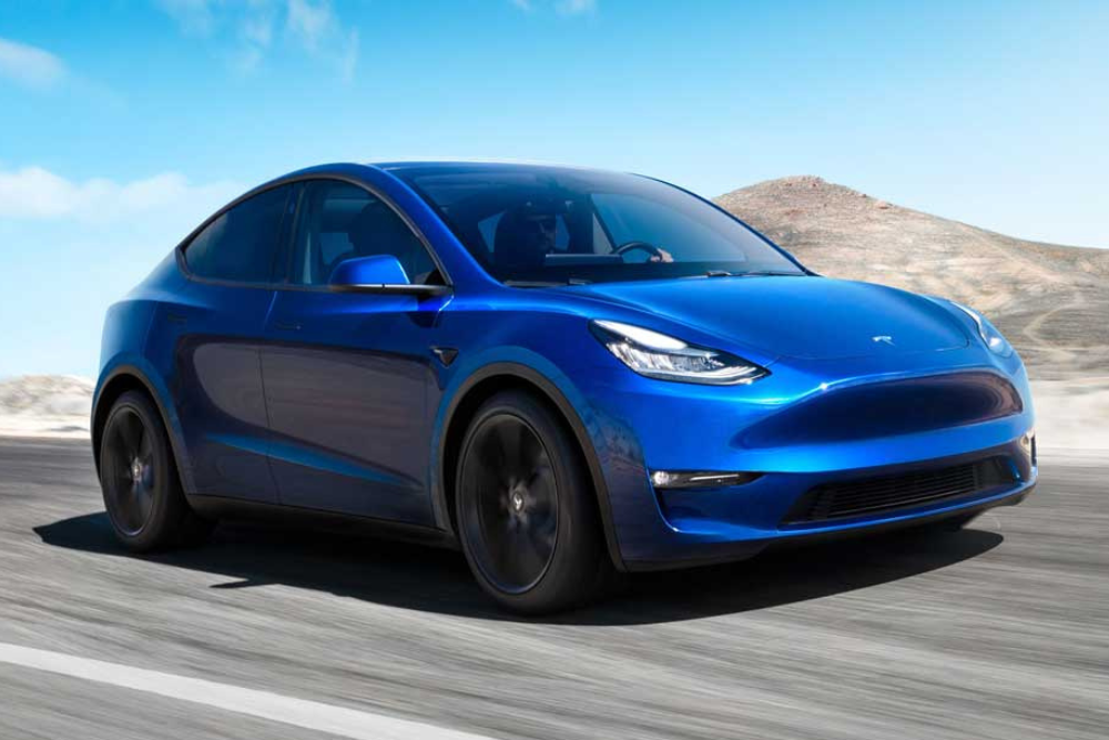 Blue Tesla Model Y driving on a sunny day