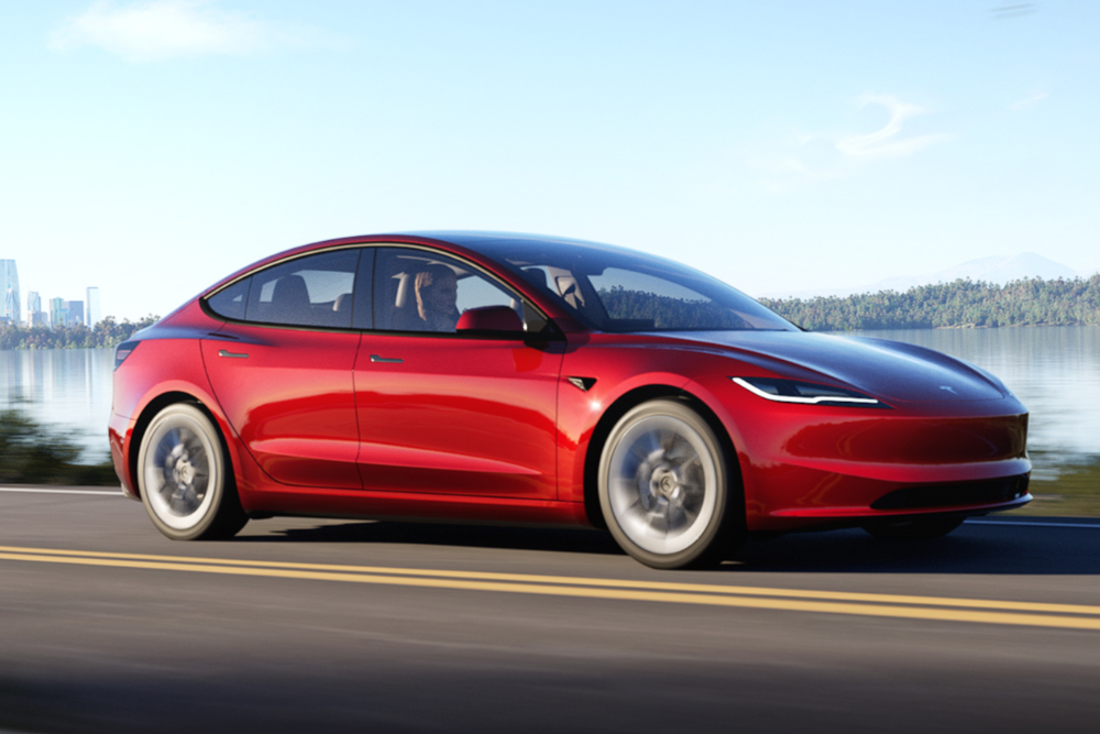Red Tesla model 3 driving on road