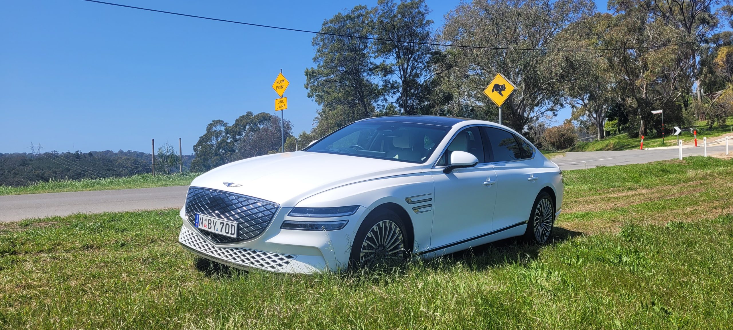 Matte White 2024 Genesis G80 electric front angle view on street