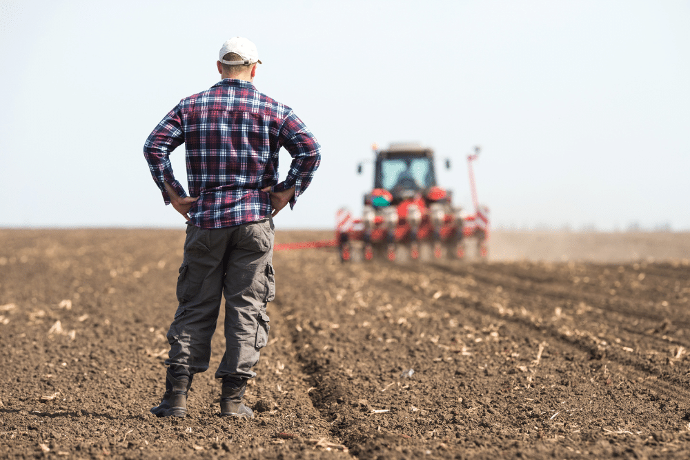 Farmer watching a tractor operate on his farmland