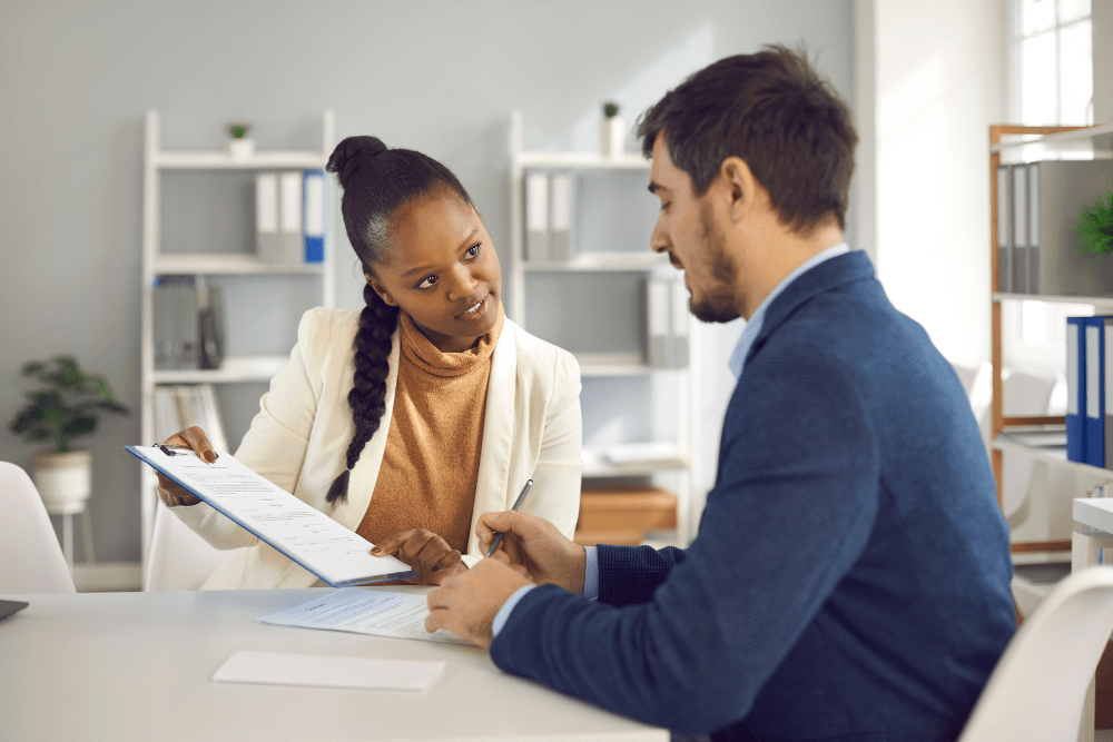 Two business people signing paperwork at the office