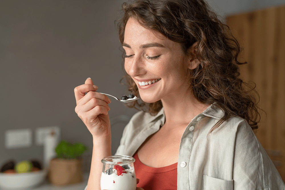 Woman smiling and eating yoghurt