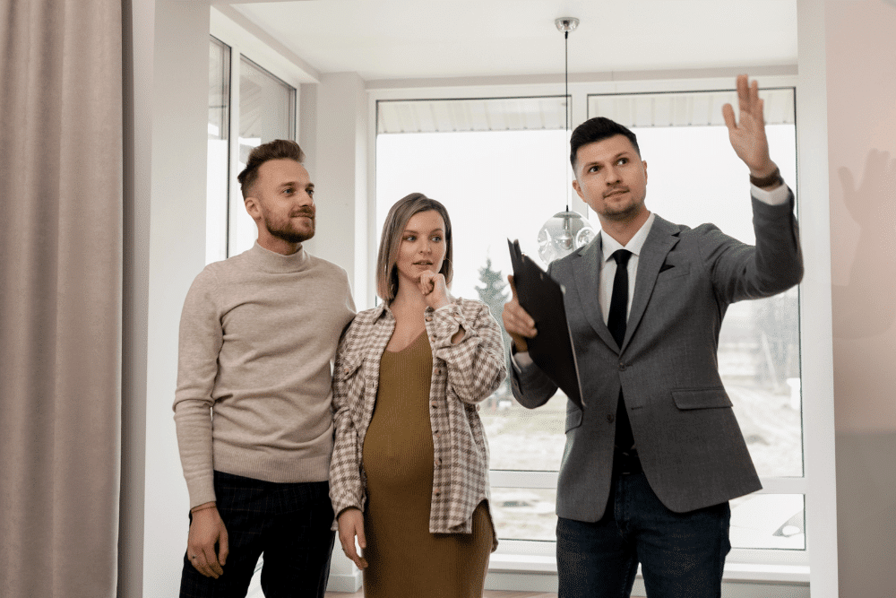 Young pregnant couple looking at a house with a real estate agent