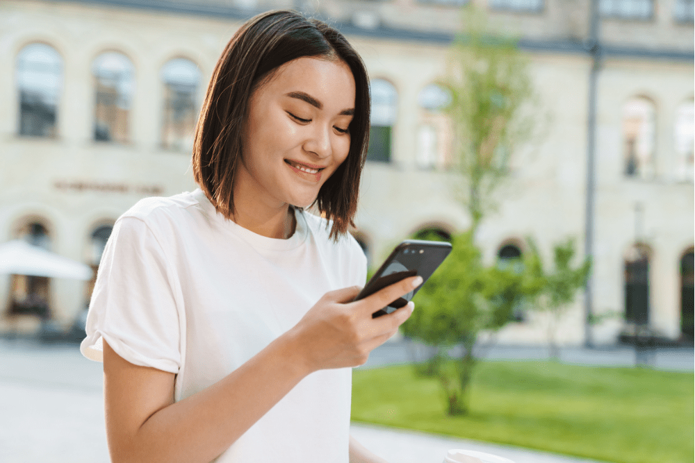 Woman smiling at her phone in the street