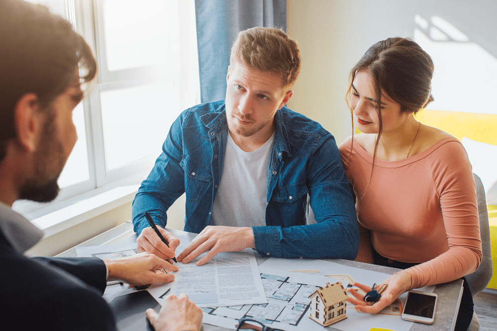 Couple signing a mortgage contract at a desk with a mortgage representative