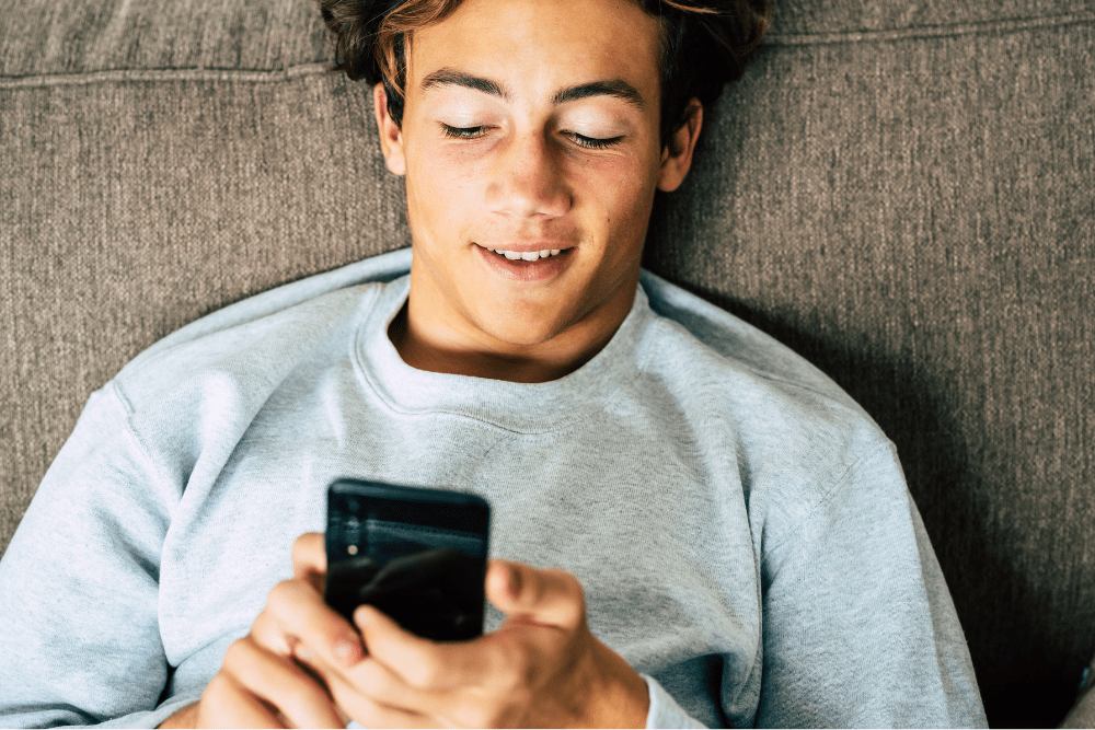 Teenage boy smiling at his phone