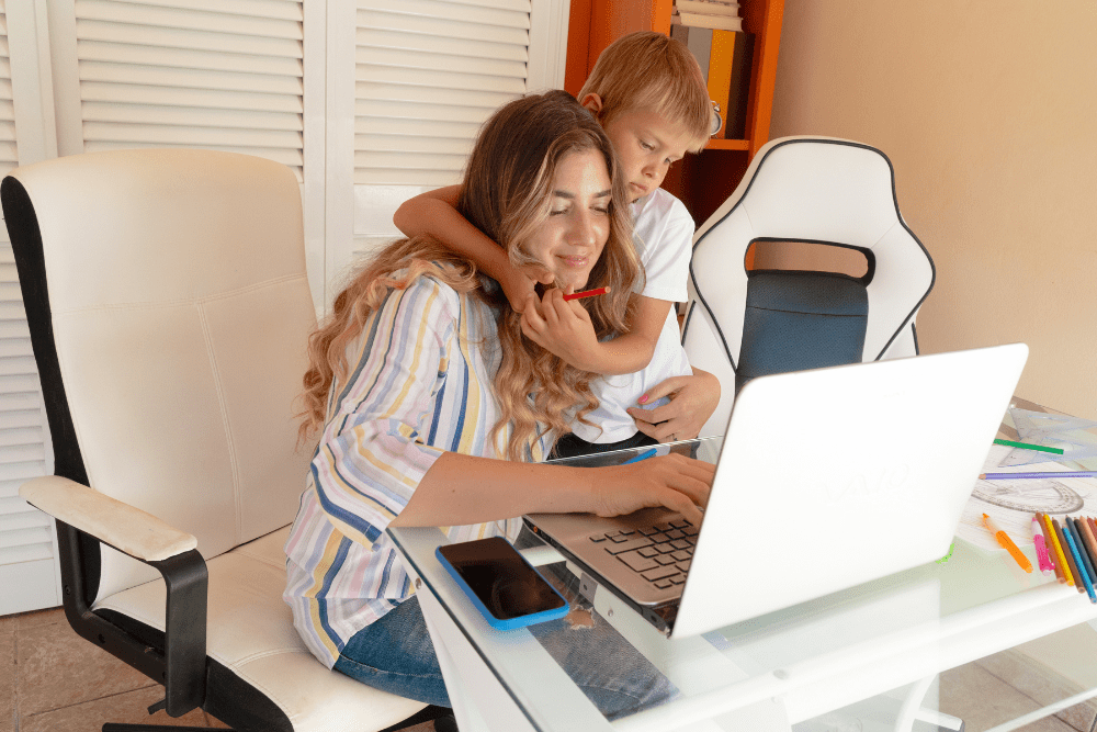 Woman working at her desk being hugged by her son