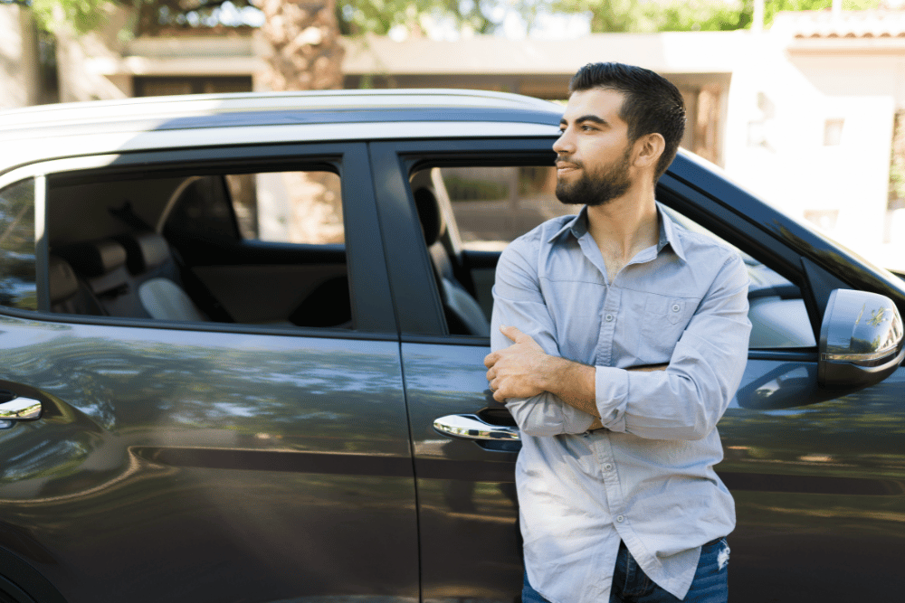 Man leaning against his car, looking into the distance