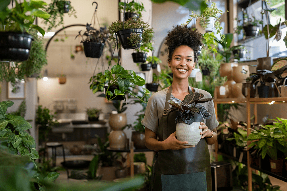 Woman smiling inside a room of pot plants