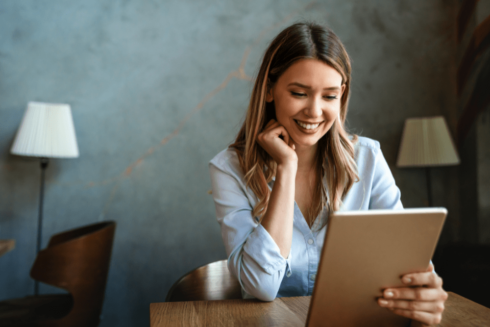 Woman smiling looking at her tablet at her desk