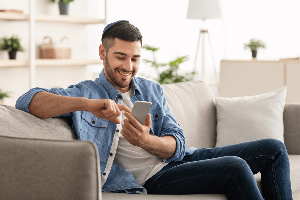 Man sitting on the couch smiling at his phone