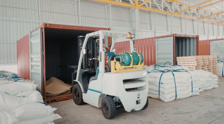Forklift sitting in a warehouse with shipping containers