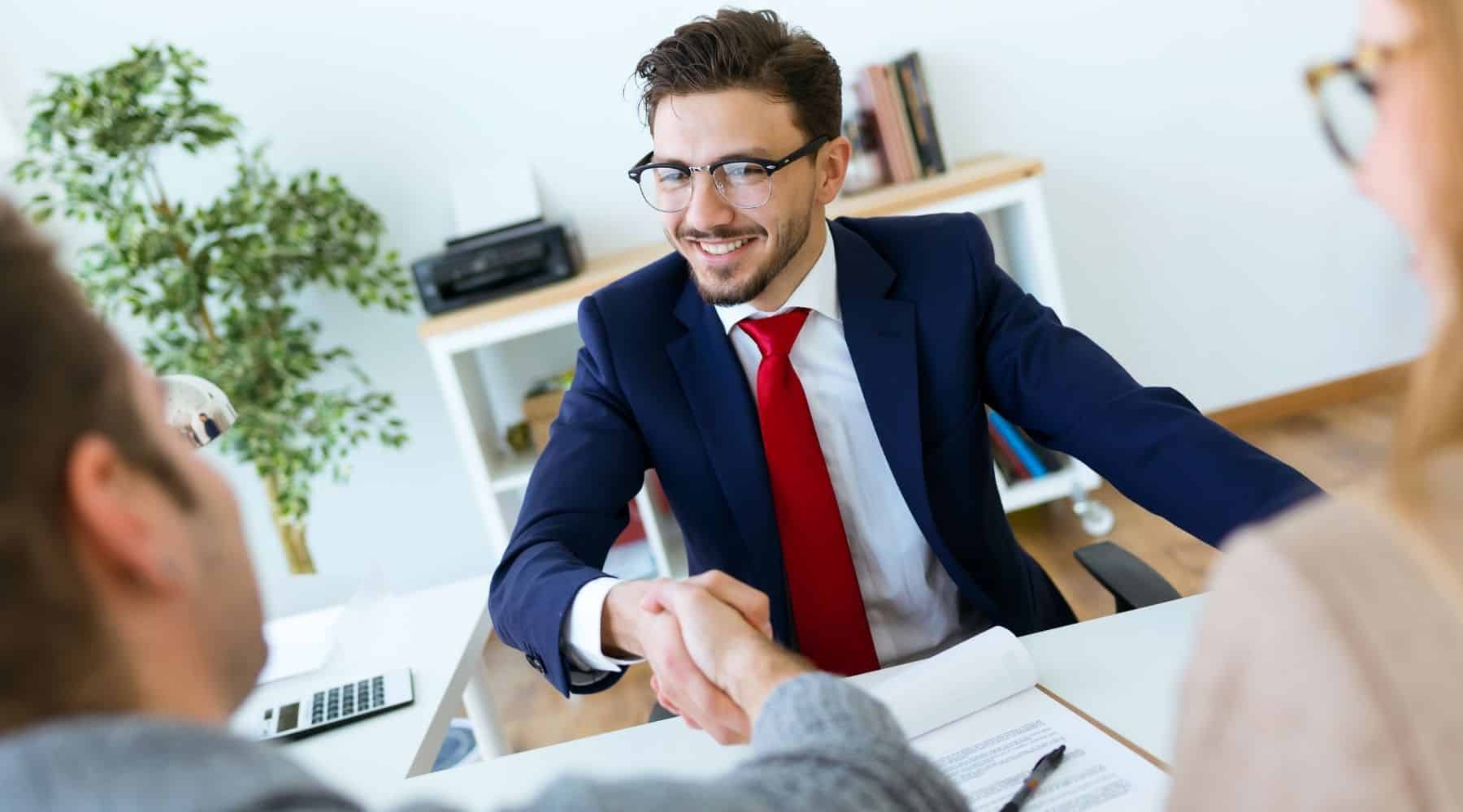 Man shaking hands with clients in office.