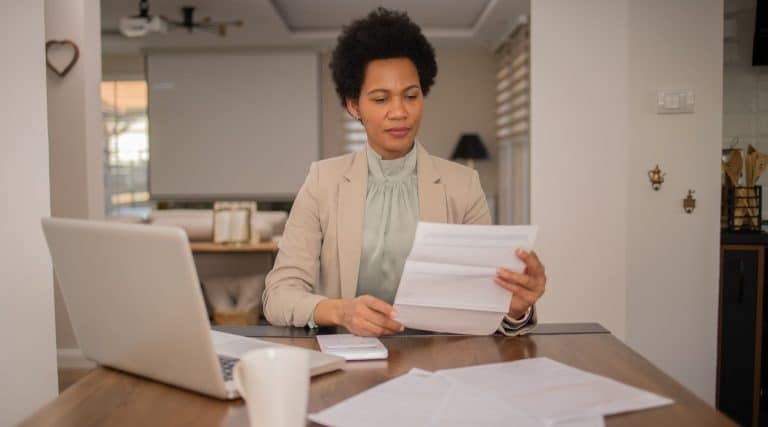 Businesswoman looking at documents with her laptop