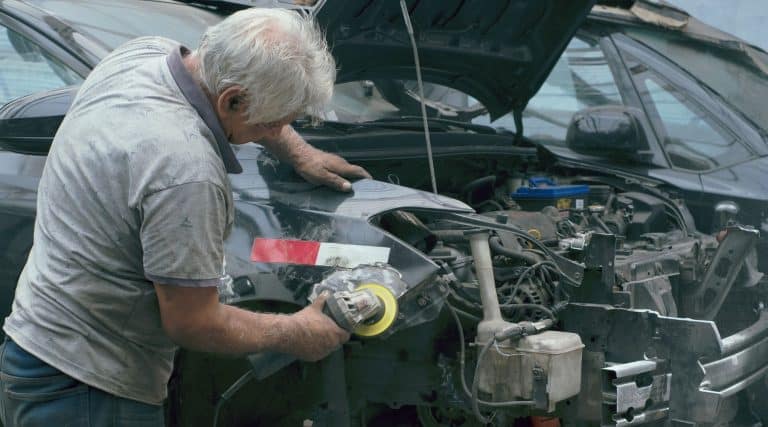 Older man repairing a car in a workshop
