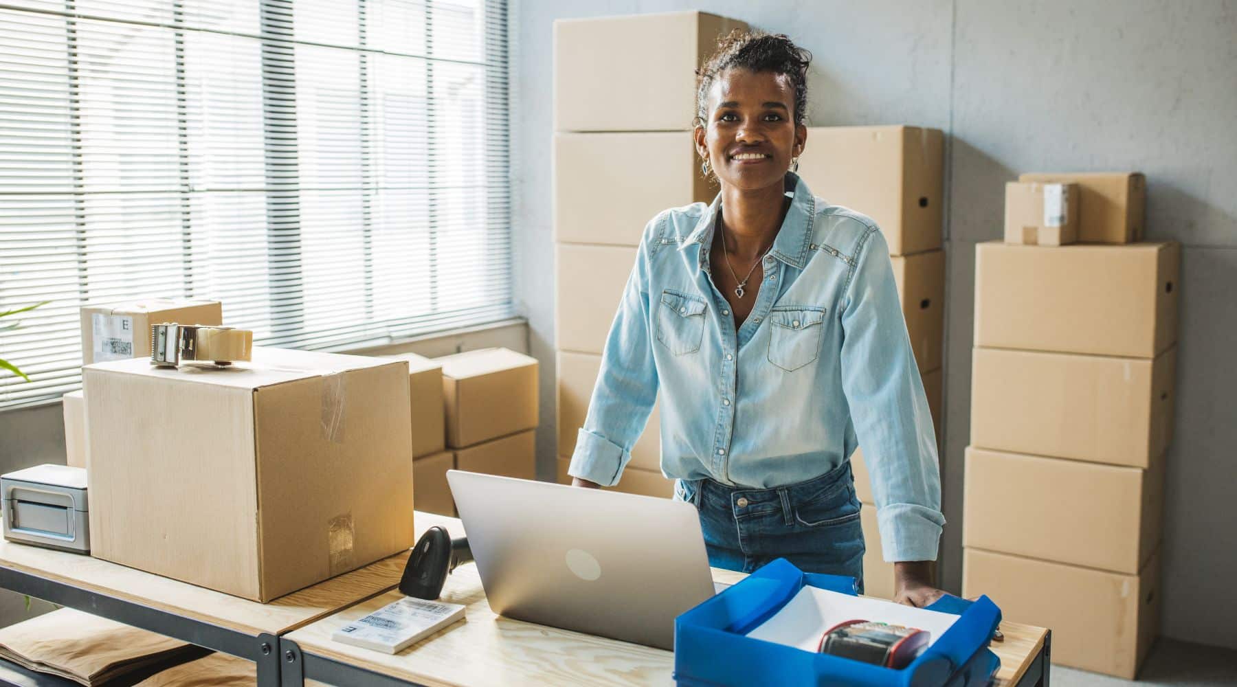 Business owner standing with boxes in her new office