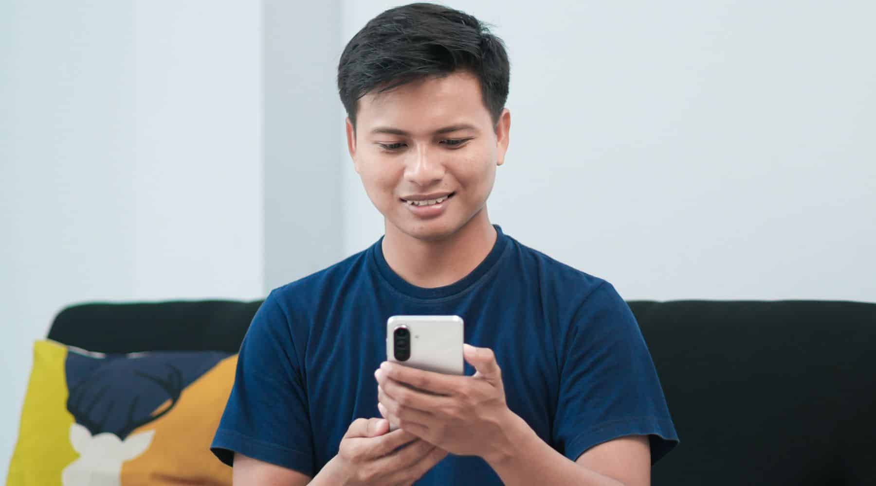 Man smiling at his phone on the couch