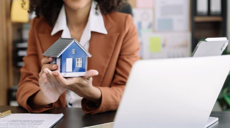 Mortgage broker holding a miniature model house in her hand
