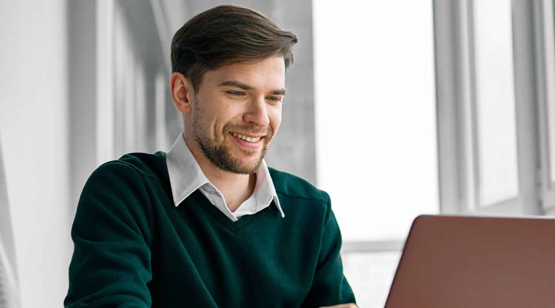Man smiling at his laptop