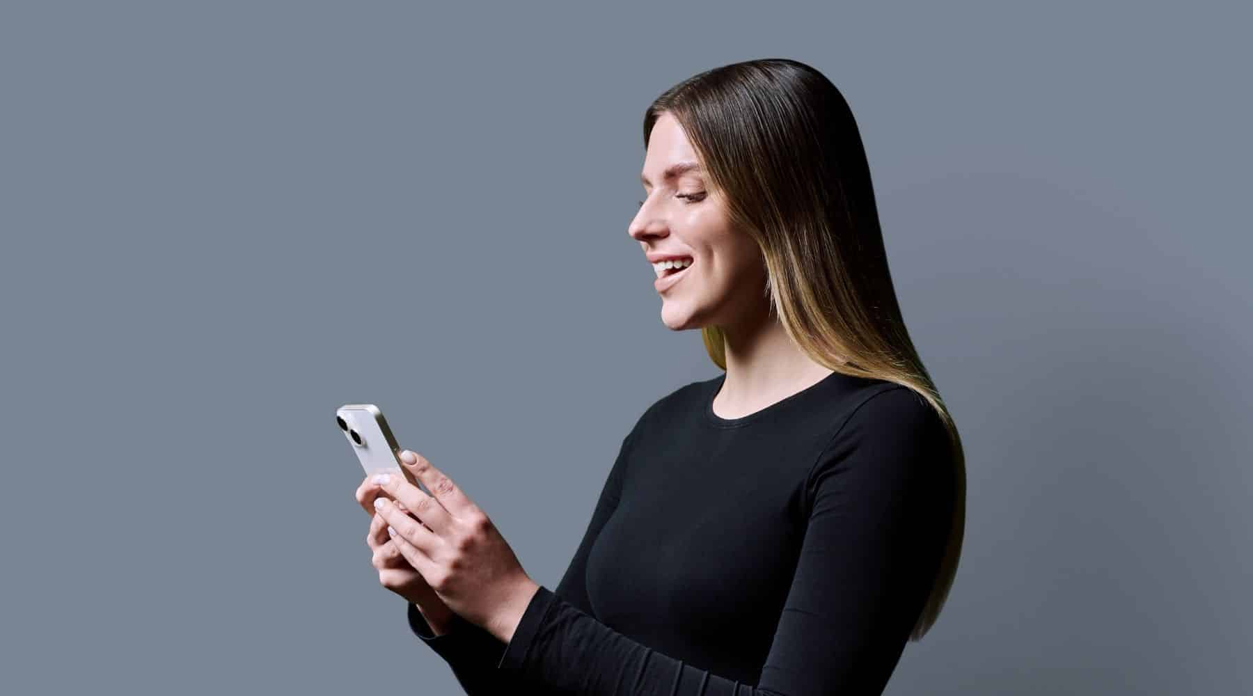 A smiling woman looking at her phone