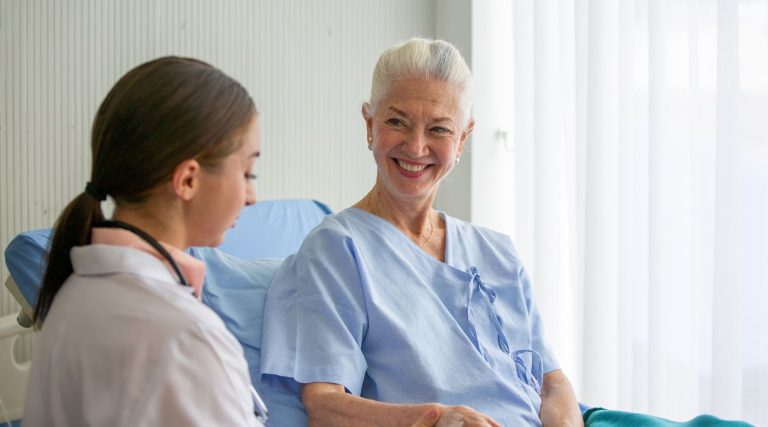 Woman in hospital bed speaking to health professional