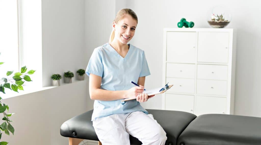 A health professional sitting on treatment bench