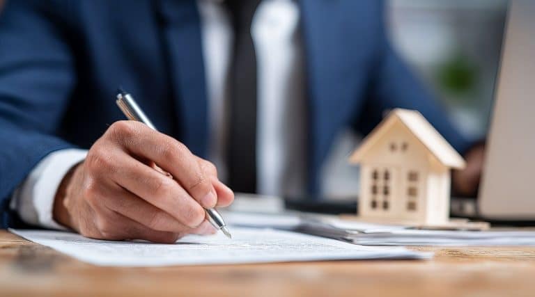 Man signing a contract next to a miniature house