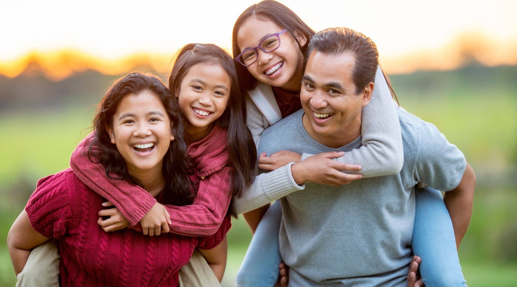 Parents piggybacking their daughters while smiling