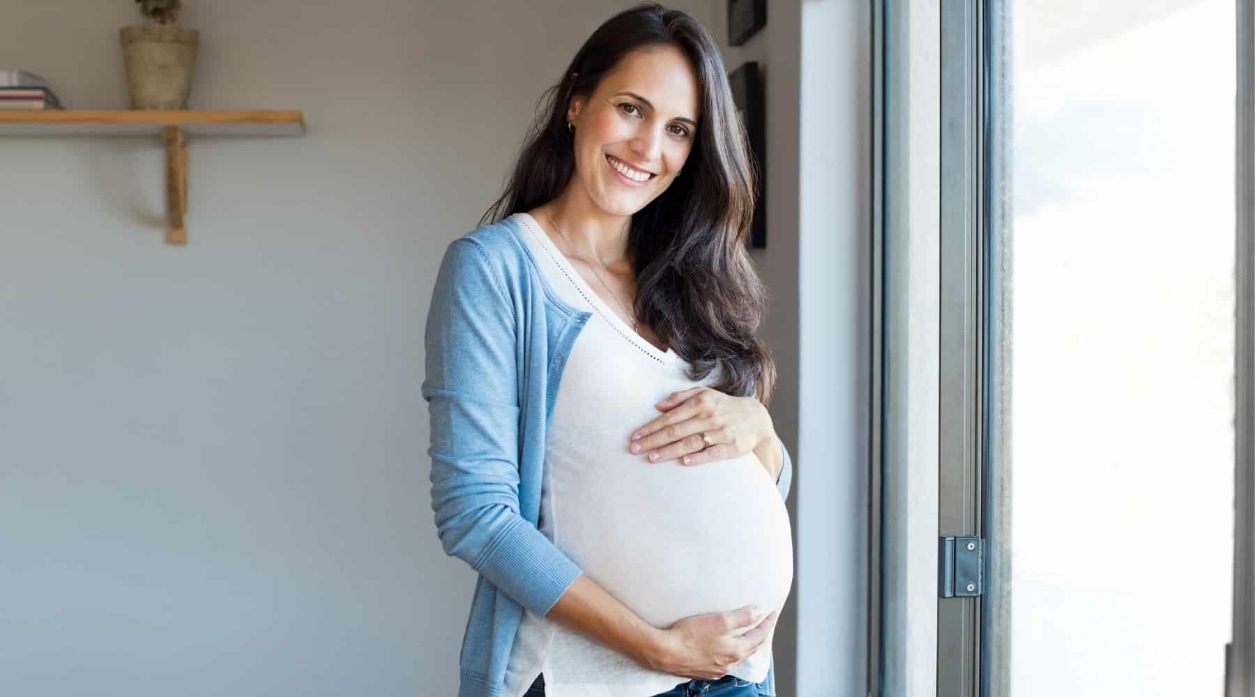 Happy pregnant woman holding her bump