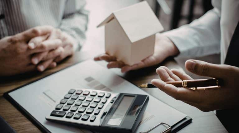 Two people with model home and calculator