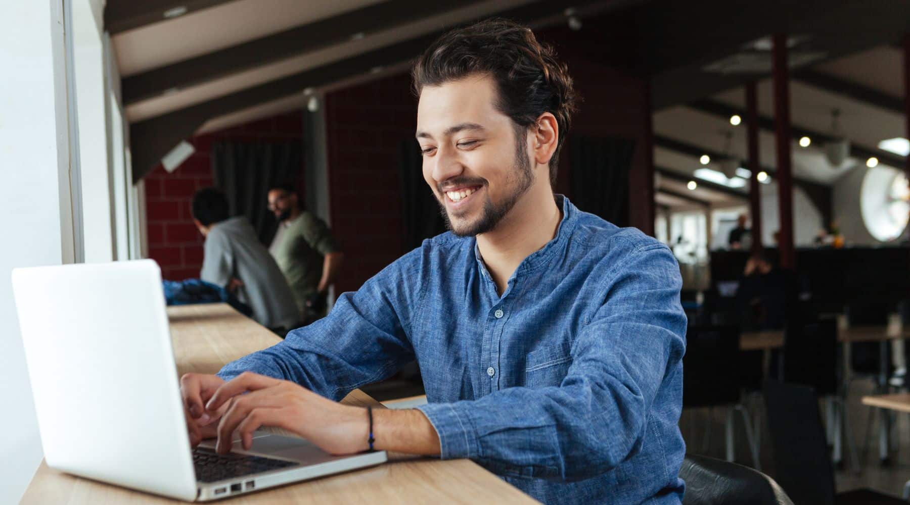 Man smiling while working on his laptop