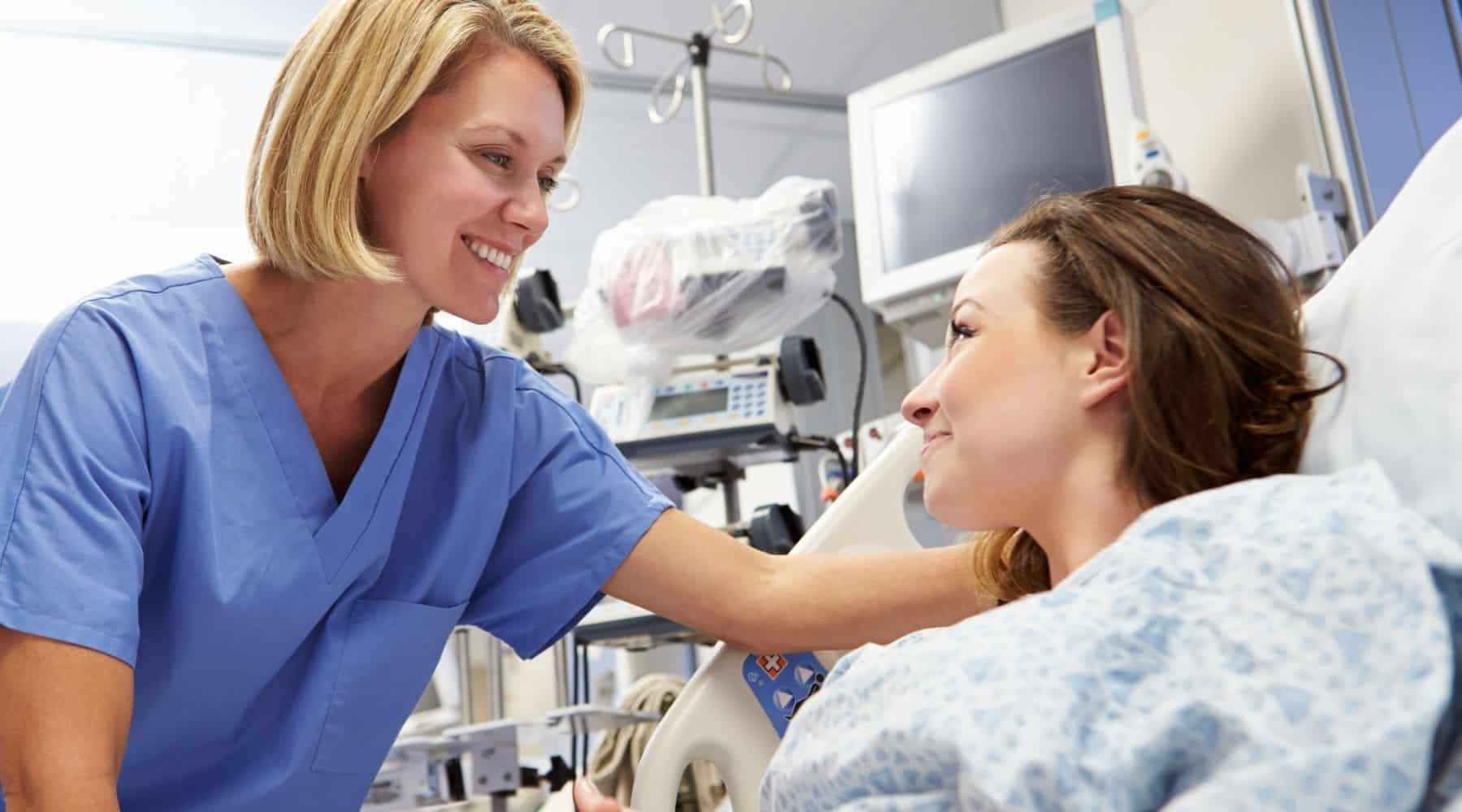 Woman in hospital bed being treated by healthcare practitioner
