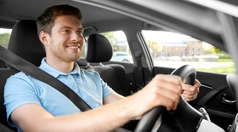 Young man smiling while driving his car