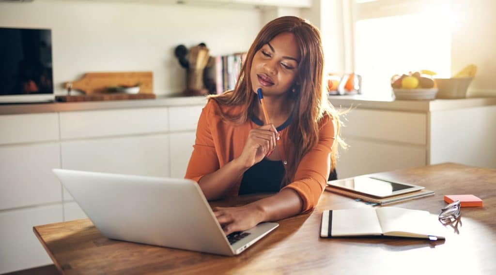 Woman looking at her laptop sitting at her dining table