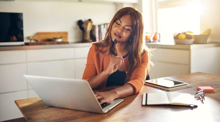 Woman looking at her laptop sitting at her dining table